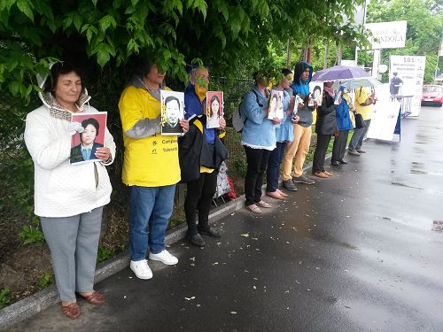法輪功學員手持被迫害致死學員的照片在使館前抗議