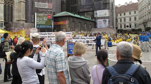 圖2：二零一五年九月十九日上午，歐洲法輪功學員在維也納斯特凡大教堂前廣場舉行反迫害、聲援全球控江集會，主持人在向廣場上的民眾介紹聲援全球控江的重大信息