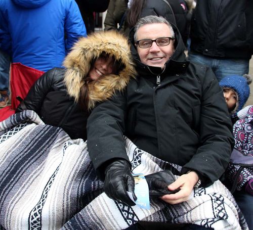 圖10：多倫多的Paul和妻子裹著被子在看遊行，他說：「天國樂團的演奏非常震撼人心，令我感慨的是這麼冷的天他們還能吹得這麼好聽，在給在寒冷中的我們帶來溫暖。」