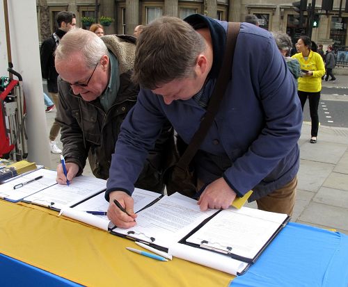 圖4：退休圖書館員麥考義（McCoy，左）先生在倫敦聖馬丁廣場簽名支持法輪功反迫害