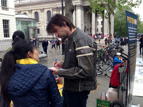 圖8：來自美國拉斯維加斯的邁克在倫敦聖馬丁廣場第一次了解法輪功真相，他在舉報江澤民的徵簽表上簽名