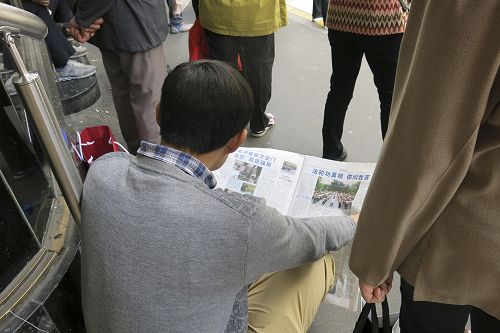 圖2：一名大陸遊客坐在商場門前的台階上認真地閱讀真相資料，了解法輪功真相。