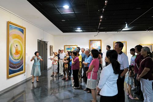 民眾專注的聆聽導覽員謝春華老師解說畫作。
