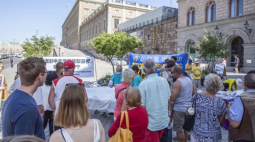 在斯德哥爾摩最熱鬧的皇宮旁的錢幣廣場，法輪功學員向民眾講真相，揭露中共迫害。