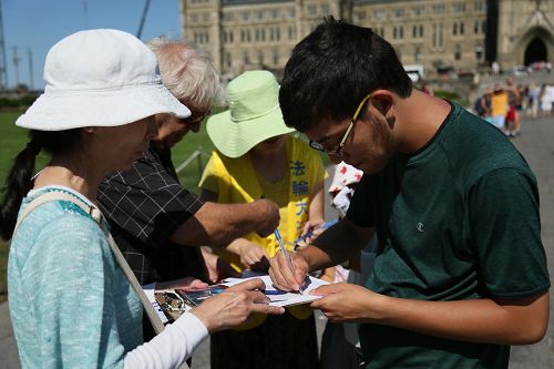 '圖2-5：八月二十六日，法輪功學員在加拿大首都渥太華國會山徵簽，呼籲即將訪華的加拿大總理敦促中共停止迫害。'