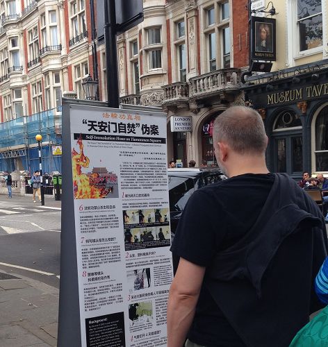 圖2：遊客駐足觀看閱讀擺在大英博物館門前人行道旁的法輪功真相展板