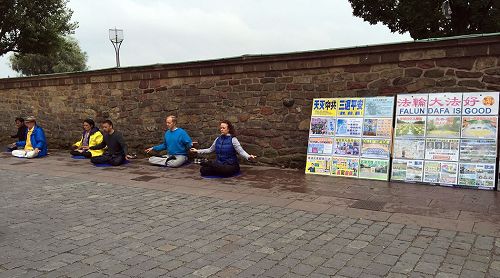 '圖1：法輪功學員在斯德哥爾摩市政廳大門口前的真相點向遊客演示法輪功五套功法'