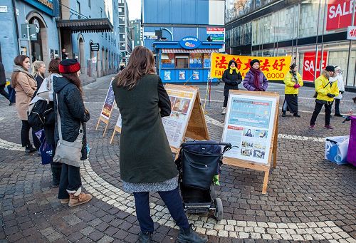 '圖1～2：在斯德哥爾摩繁華的鬧市區（Hötorget）法輪功學員舉辦弘法講真相活動，民眾觀看真相展板，了解真相。'