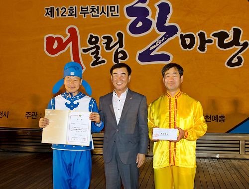 '圖6：韓國京畿道議會文化觀光委員長（中）給參加本次慶典活動獲一等獎──最優秀獎的法輪功團體頒獎。'