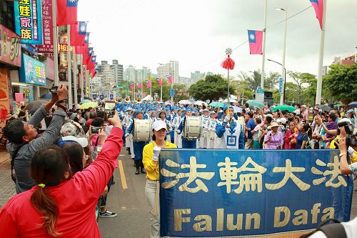 '圖1：十月七日新北市舉辦淡水環境藝術節踩街活動，台灣法輪大法隊伍最受矚目，吸引數萬民眾駐足觀看，並紛紛拿出手機拍照留影。'