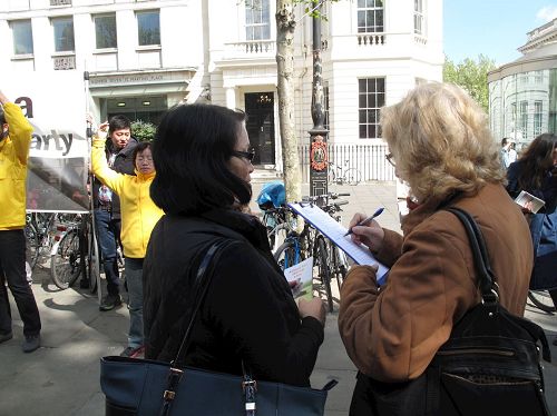 '圖16：二零一七年四月二十二日，退休教師約翰遜女士在聖馬丁廣場被法輪功學員的平和抗議所吸引，了解真相後簽名反迫害'
