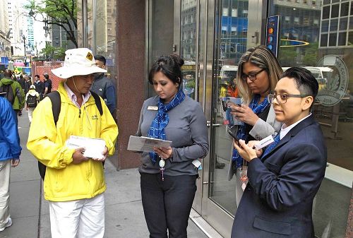 '圖11：幾位銀行職員站在店門前觀看遊行，了解真相後簽名反對中共活摘法輪功學員器官。'