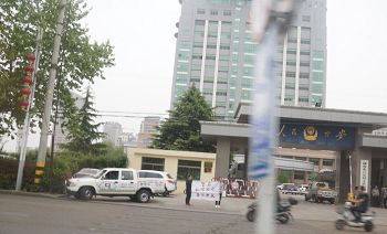 洪煥芹的兩個女兒在文登區公安局門口打出「警察私闖民宅綁架」的橫幅