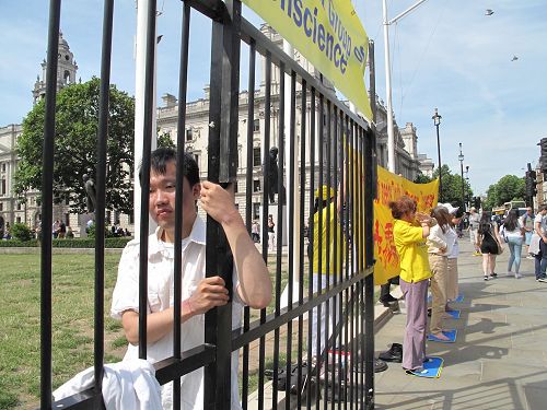 '圖5：二零一七年七月十八日，楊博士在英國議會大廈前扮演模擬牢籠中的學員'