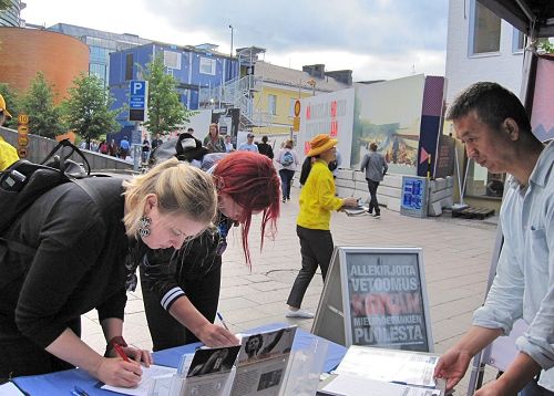 '圖3～7：當天下午，芬蘭學員又來首都市中心向當地民眾和遊客介紹法輪功的真相。不少民眾駐足了解，並簽名支持制止迫害。'