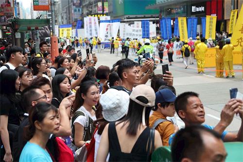 '圖16：遊行吸引沿路民眾，許多人拿起手機拍攝盛況。'