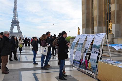 '圖1～2：二零一八年十一月四日，法輪功學員冒著寒風在巴黎艾菲爾鐵塔的人權廣場上傳播法輪功的真相。許多遊人駐足了解真相。'