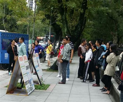 '圖1～3：台灣法輪功學員在台北國父紀念館前向過往遊客傳播法輪功的真相。不少大陸遊客駐足觀看真相展板。'