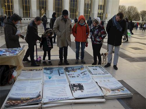 '圖1～2：二零一八年十二月九日下午，在巴黎人權廣場，遊人閱讀法輪功真相展板'