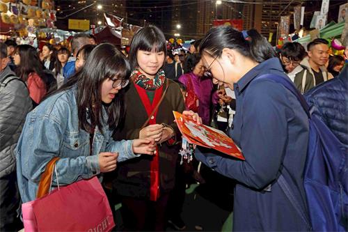 '圖11：法輪功學員向民眾派發福字帖、真相小蓮花與真相資料。'