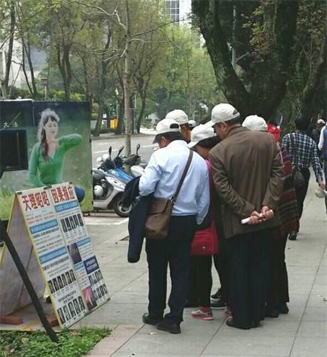 '圖：大陸遊客在台灣國父紀念館前認真觀看法輪功真相展板'