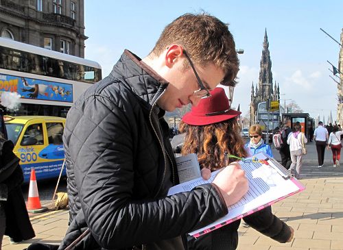 圖8：蘇格蘭青年麥克蘭•卡特（Mclain Carter）正在呼籲制止中共活摘法輪功學員器官的徵簽表上簽名。