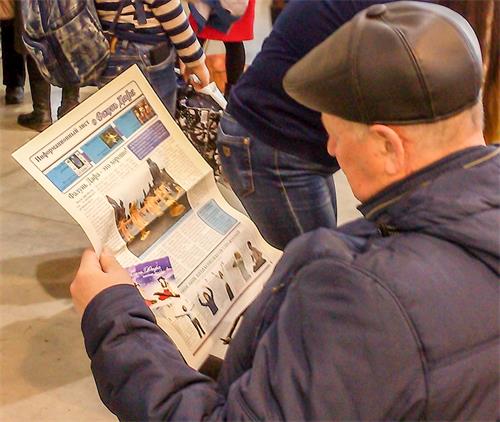 '圖2：一民眾在閱讀介紹法輪功的報紙'