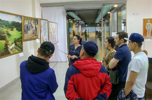 '圖1～2：在俄羅斯克拉斯諾亞爾斯克市（Krasnoyarsk）的「真善忍美展」上，人們觀賞畫作，了解法輪功真相。'