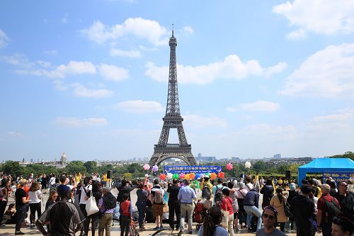 圖3 ：五月二十日，法國法輪功學員在法國巴黎人權廣場慶祝法輪大法日，吸引過往的遊客和法國民眾駐足觀看、拍照、攝像。
