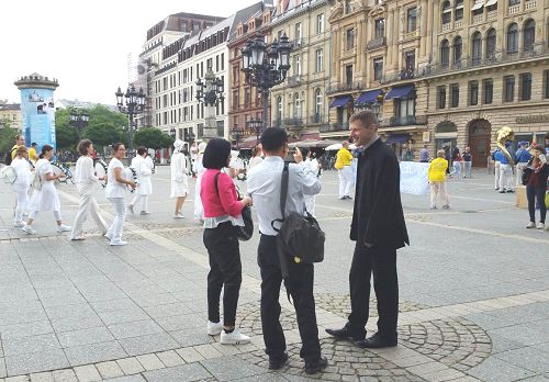 圖2：法輪功學員的遊行隊伍吸引大陸遊客駐足觀看並攝影。這位西方學員（右側深衣者）在用流利的中文給他們講真相。