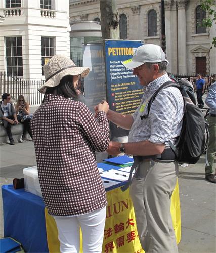 圖8：二零一八年六月二十三日，在倫敦聖馬丁廣場，來倫敦參加活動的彼得（Peter）聽法輪功學員講真相，非常高興地接過法輪功學員送給他的手工蓮花。