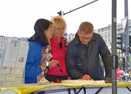 '圖4：一對來自瑞典的遊客在徵簽簿上簽字支持反迫害'