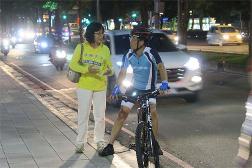 '圖4：法輪功學員正在向一位停下腳步關注的自行車騎士解說活動意義。'