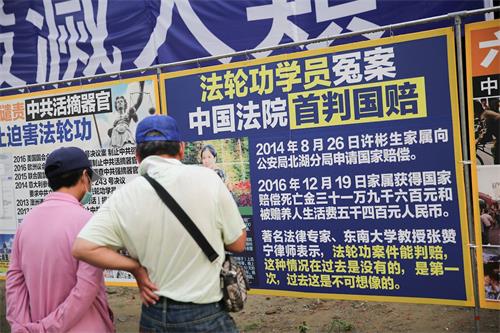 '圖11：來自台南西港的市民郭先生夫婦第一次遇到法輪功，沿著真相展板一片片非常仔細的閱讀著，並呼籲公安明智抉擇。'