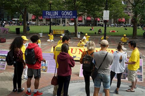 '圖3：波士頓市科普利廣場上，民眾駐足觀看法輪功學員煉功'