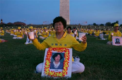 '圖5：王春榮女士面前擺放著孫蓮霞的照片，她雙手舉起蠟燭，悼念曾經相識的這位同修。'
