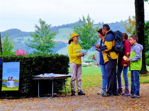 '圖2：部份瑞士法輪功學員在伯爾尼景點玫瑰園（Rosengarten）煉功，向遊客傳播法輪功的真相，不少遊客駐足了解。'