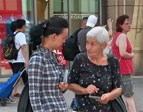 '圖10：這位老年女士（右）拿著介紹法輪功和揭露中共迫害的傳單，詢問學員（左）有關法輪功的真相。'