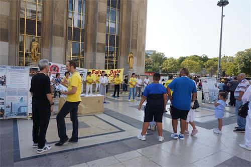 '圖6：8月19日，巴黎部份法輪功學員在人權廣場上和過往世界各國的遊客交談'
