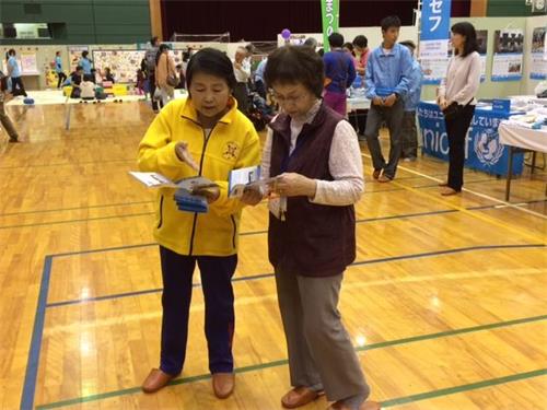 '圖1～2：法輪功學員在日本稻澤市福祉宣傳活動中向過往的市民介紹功法'