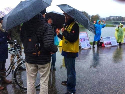 '圖7：波蘭法輪功學員在雨中向遊客講真相'