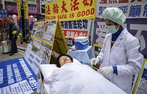 '圖：二零一三年一月十二日，法輪功學員在香港的一個購物區模擬中共強摘器官暴行。他們說他們的同修受到酷刑迫害，並被強摘器官。'