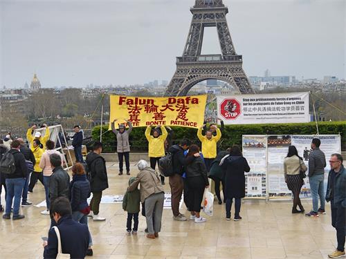 '圖1：三月二十四日下午，人權廣場人流不斷，法輪功學員在巴黎的人權廣場進行煉功和講真相的活動。人們被法輪功學員安靜、祥和的煉功吸引，不少遊客駐足了解真相。'