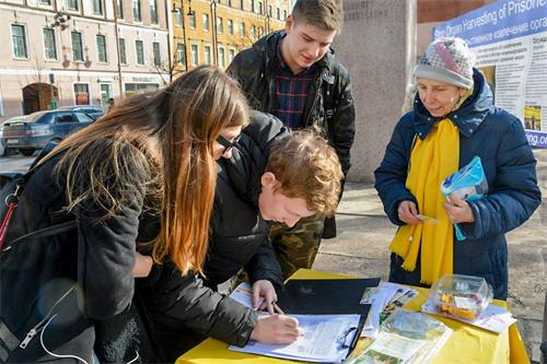 '圖1：俄羅斯聖彼得堡市中心，路人簽名支持法輪功學員反迫害。'