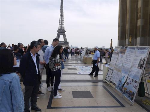 '圖8：為紀念四二五和平上訪二十週年，法輪功學員在巴黎人權廣場進行了講真相的活動。圖為遊人觀看真相展板。'