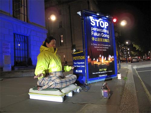 '圖1： 二零一九年四月二十五日夜，法輪功學員高女士在倫敦中使館前平抗議，法輪功學員在這裏的持續和平抗議始於二零零二年六月。'