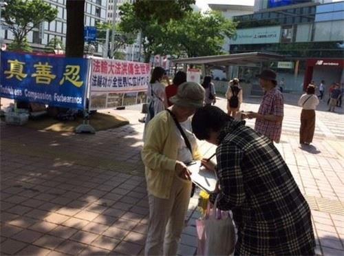 '圖1～2：法輪功學員在日本愛知縣首府名古屋市舉辦活動講真相，慶祝世界法輪大法日。民眾明真相後，簽名聲援法輪功。'