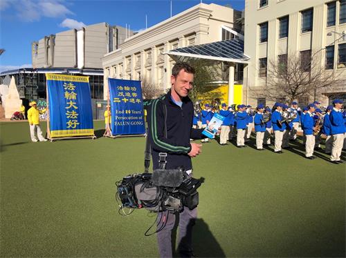 '圖9：新西蘭電視台攝影師山姆鼓勵法輪功學員堅持不懈，奮戰到底。'