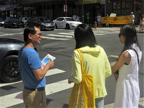 '圖4：兩位年輕華裔在了解法輪功是甚麼'