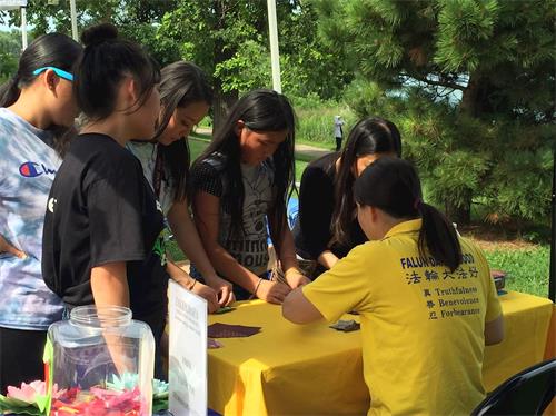'圖2：很多亞裔年輕人圍著法輪功學員學做紙摺蓮花'